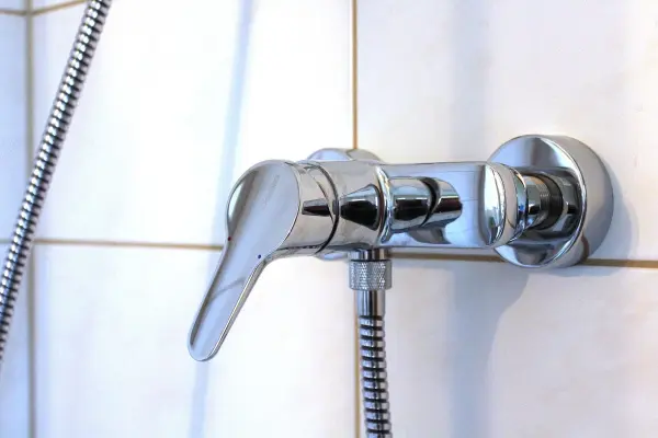 Ein glänzender Wasserhahn wird mit Teflonband abgedichtet, um Gewindeverbindungen gegen Leckagen zu sichern.