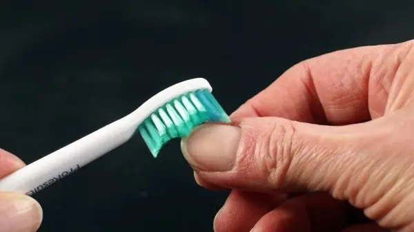 Eine Hand hält eine elektrische Zahnbürste, die gerade über Fingernägel gestrichen wird, um diese sauber zu halten.