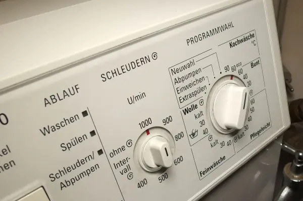 Eine Waschmaschine mit verschiedenen Einstellungen steht im Vordergrund, während ihre Tasten nicht mehr reagieren.