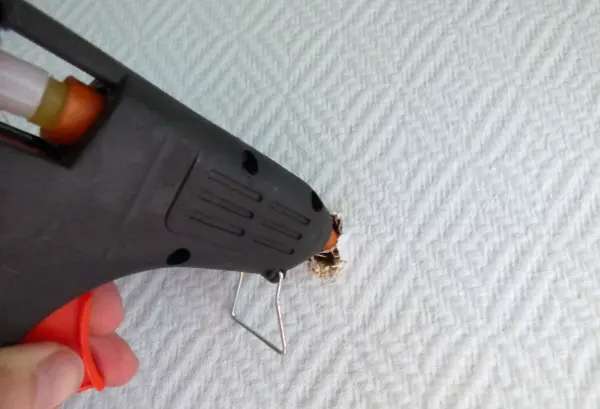 Eine Heißklebepistole wird auf eine strukturierte Oberfläche gerichtet, um ein Bohrloch schnell zu reparieren.