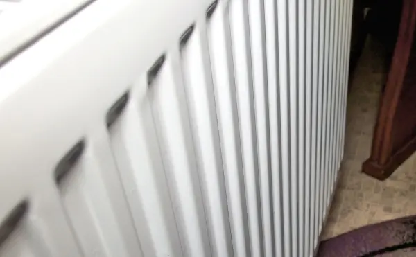 Eine warme Heizung wird sichtbar entlang eines Fensters betrachtet, ideal zum Streichen in einem Raum mit Teppichboden.
