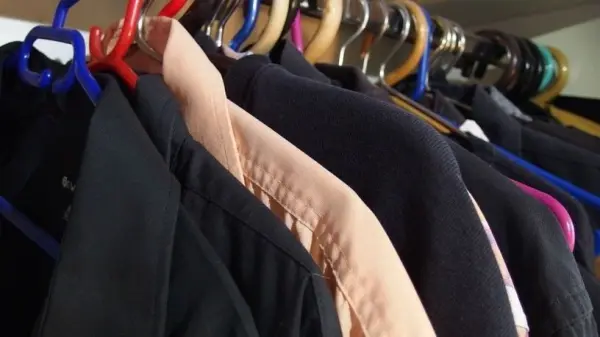 Hängende Kleidungsstücke in einem Kleiderschrank zeigen einen Ausmist-Prozess für den Männerkleiderschrank.