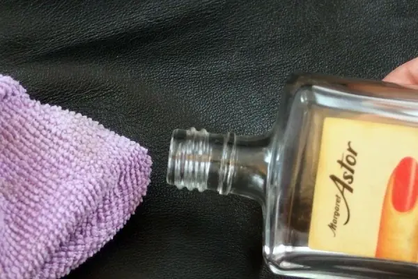 Eine Leder-Aktentasche wird mit einem Reinigungstuch und einer Flasche zum Entfernen von Kratzern behandelt.