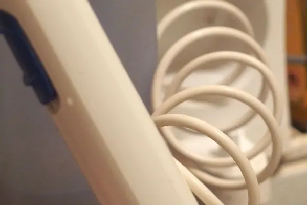 Ein brauner Mundduschenschlauch ist sichtbar und hängt in einer Spirale, bereit zum Einsatz in einem Badezimmer.