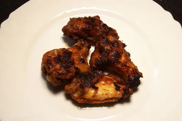 Krosse Chicken Wings liegen appetitlich auf einem weißen Teller und sind bereit zum Genießen.