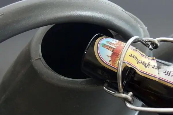 Ein Bierflasche wird in eine Gießkanne eingefüllt, um als Blumendünger im Garten verwendet zu werden.