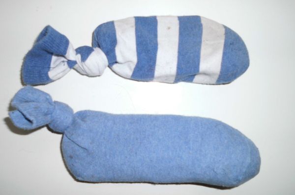 Zwei blaue Socken, eine gestreift und eine einfarbig, sind zu Stäben geformt, die zur Schuhpflege verwendet werden.