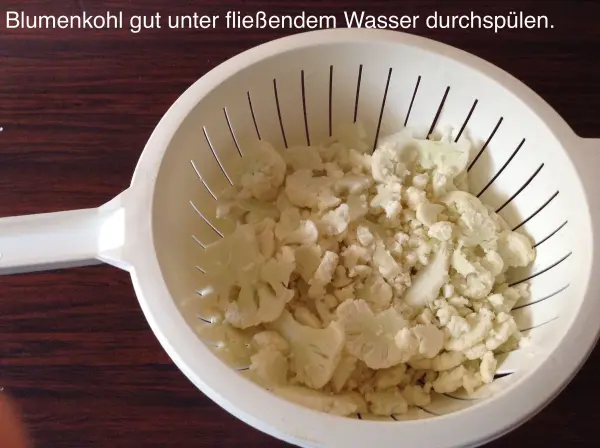 Blumenkohl wird in einem Sieb gut unter fließendem Wasser durchgespült und zeigt sich frisch und bereit zum Kochen.