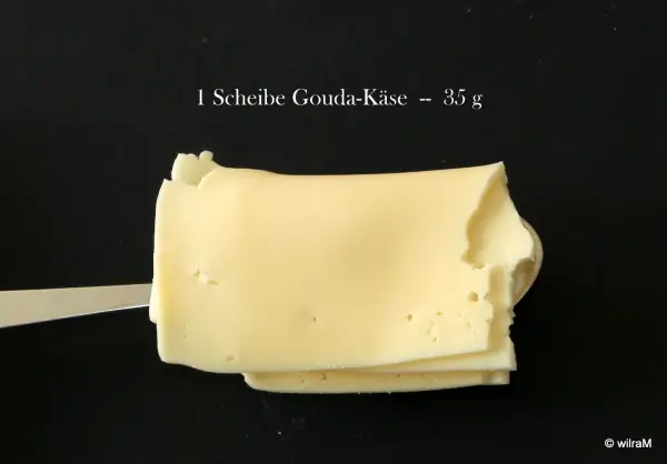 Eine Käsescheibe liegt auf einem Teller, während ein Maßstab angibt, dass sie 25 g wiegt. Ideal zum Mengen abmessen ohne Waage.