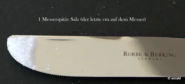 Ein Messlöffel liegt bereit, um Zutaten abzumessen, während ein Text über die Verwendung ohne Waage im Hintergrund sichtbar ist.