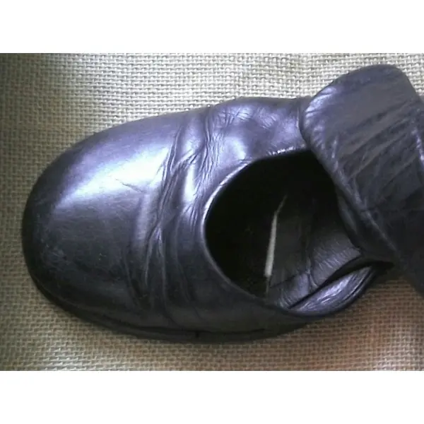 Schwarze Schuhe liegen auf einem Untergrund, bereit, Slipeinlagen zur Verbesserung des Tragekomforts einzulegen.