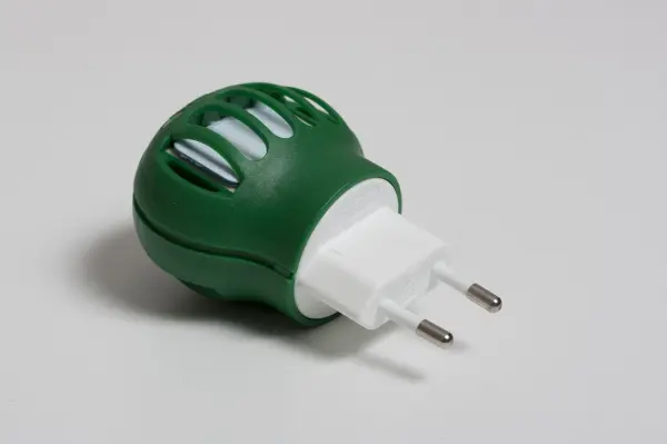 Ein Mückenstecker in Grün mit weißen Einsätzen steht bereit, um Stechmücken in einem Innenraum abzuwehren.