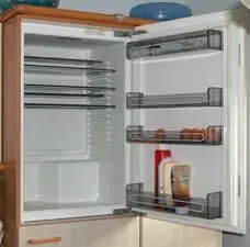 Ein geöffneter Kühlschrank zeigt leere Regale und einige Utensilien, während er gereinigt und ausgemistet wird.