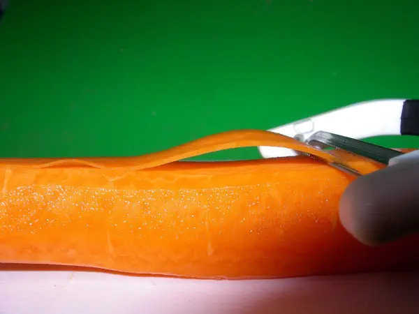Mit einem Sparschäler lassen sich die Karotten dünn hobeln – so gelingen knusprige Möhrenchips im Backofen besonders gut.