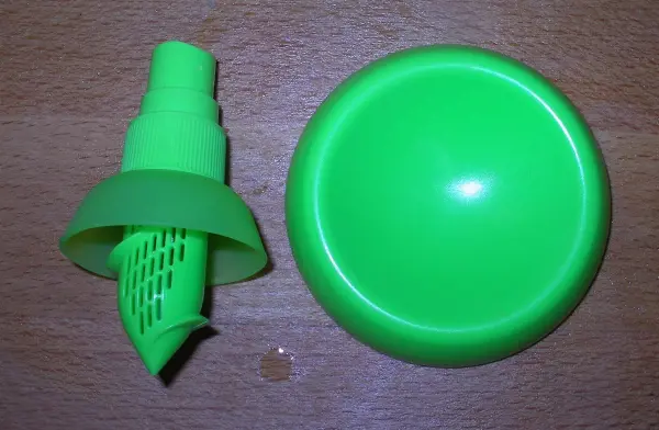 Ein grüner Gewürzsprayer liegt neben einer runden, grünen Schale auf einer Holzoberfläche, bereit, Würze zu sprühen.
