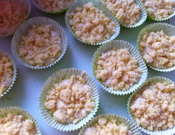 Frisch zubereitete Apfel-Zimt Muffins mit Streusel sind in Backformen angeordnet und warten auf den Ofen.