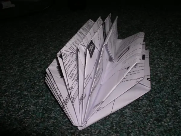 Ein gefalteter Notizhalter aus dünnem Papier steht auf einem grünen Teppich, strukturiert und kreativ in Form gebracht.