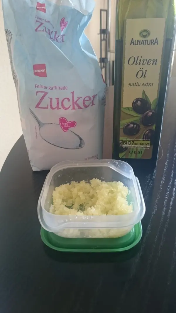 Ein Behälter mit Peeling-Mischung aus Zucker und Olivenöl steht auf einem Tisch, um eingewachsene Haare zu behandeln.