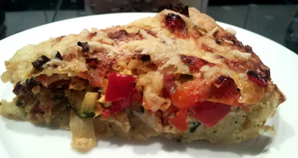 Die glutenfreie Gemüse-Quiche liegt auf einem weißen Teller, goldbraun gebacken mit frischen Gemüse durchzogen.