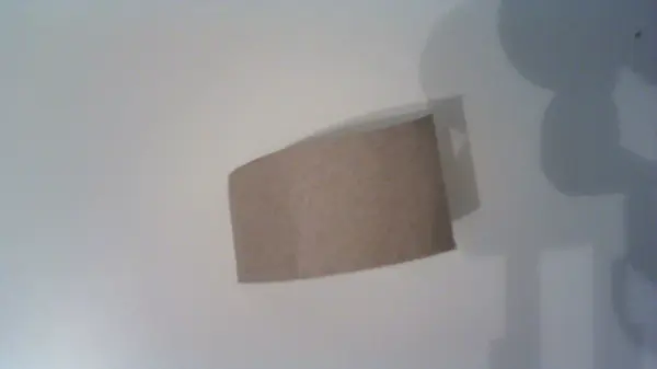 Eine einfache Flaschenmütze aus braunem Papier ruht auf einem weißen Hintergrund und verleiht einer Flasche ein kreatives Aussehen.