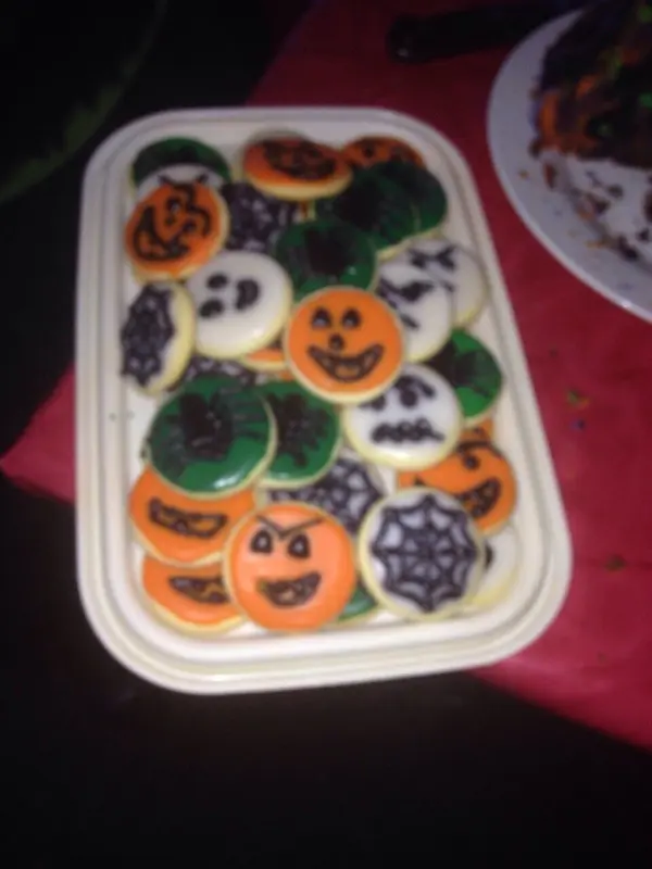 Halloween-Kekse liegen bunt verziert auf einem Tablett. Die Gesichter und Spinnennetz-Motive verstärken die gruselige Atmosphäre.