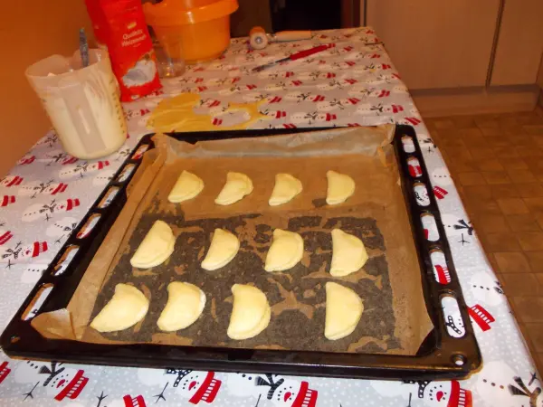 Auf einem Backblech liegen gleichmäßig angeordnete, ungebackene Muschelplätzchen, bereit zum Backen in einer häuslichen Küche.
