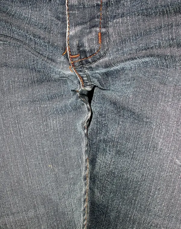 Ein Paar Jeans zeigt einen Riss an der Naht, was mit dem Thema Inkontinenz in Verbindung stehen könnte.