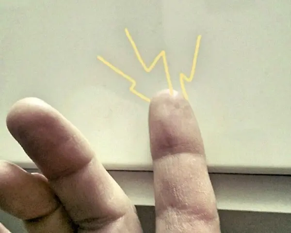 Ein Finger berührt eine Oberfläche, während gelbe Zickzacklinien statische elektrische Entladung symbolisieren.