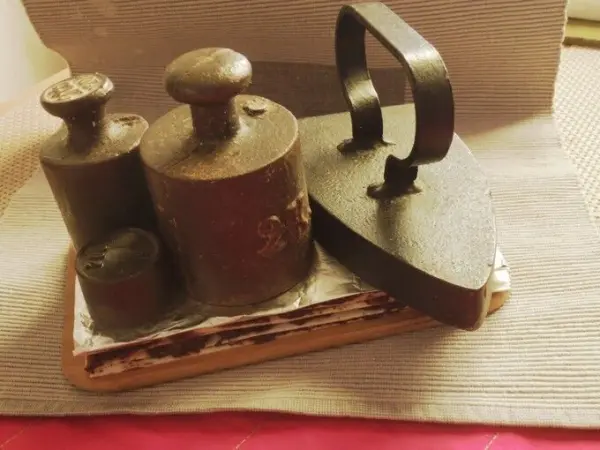 Schoko-Würfel-Konfekt liegt auf einem Holzbrett, während ein schwerer Wäschebeschwerer und ein antikes Bügeleisen daneben platziert sind.