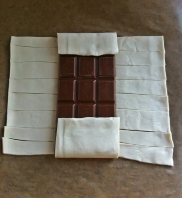 Blätterteig umschließt eine Schokolade, während sich der Strudel auf einer Arbeitsplatte vorbereitet.