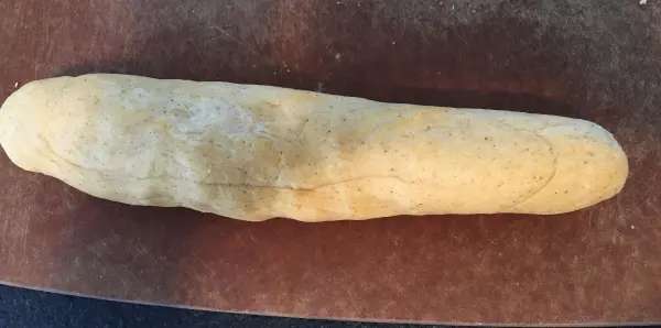 Ein geformter Schokoladenteig ruht auf einem Holzbrett, bereit für das Backen des russischen Schokoladenzopfs.
