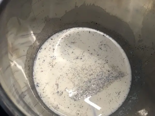 Ein Behälter enthält eine Mischung aus flüssiger Milch und feinen Schokoladenstückchen, bereit für den Schokoladenzopf.