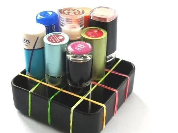 Eine Box mit Gummiband-Aufteilung hält verschiedenfarbige Fläschchen geordnet und stabilisiert sie in einem kompakten Raum.