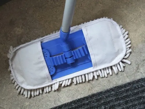 Ein Wischtuch mit blauer Halterung liegt auf einem glatten Boden und ist bereit, ihn sauber zu machen.