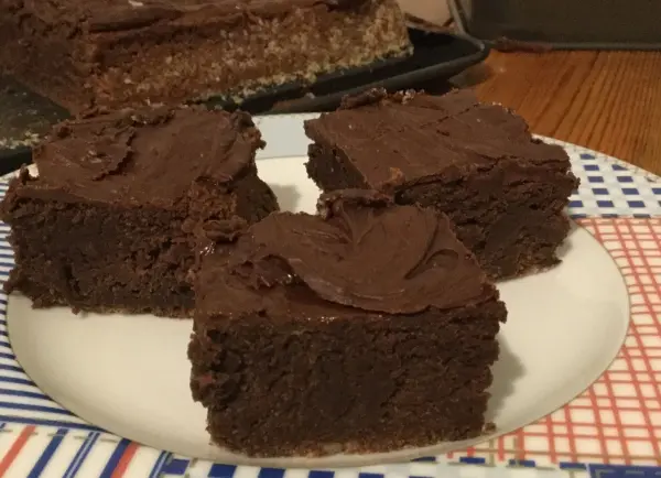 Dunkle, saftige Muffins liegen appetitlich auf einem Teller, umgeben von einem karierten Tischläufer in einer gemütlichen Küche.