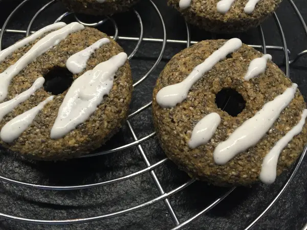 Chia Donuts liegen frisch auf einem Backgitter, dekoriert mit einer cremigen Zitronen-Kokos-Glasur.