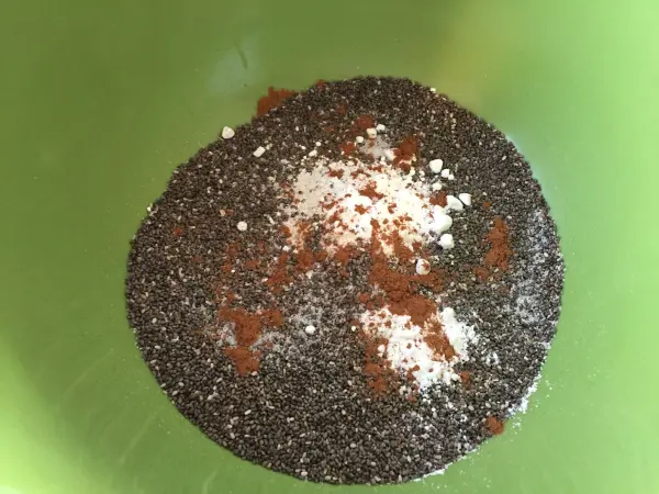 Eine grüne Schüssel enthält eine Mischung aus Chiasamen, Zucker, Zimt und weiteren Zutaten zur Herstellung von Chia Donuts.