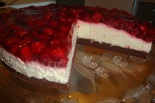 Eine köstliche Erdbeertorte mit glattem Tortenguss steht auf einem eleganten Tortenteller. Ein Stück ist herausgeschnitten.