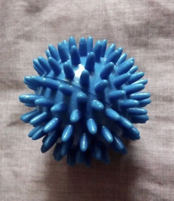Ein blauer, stacheliger Ball liegt auf einem grauen Untergrund, ideal zur Linderung von Juckreiz ohne Aufkratzen.
