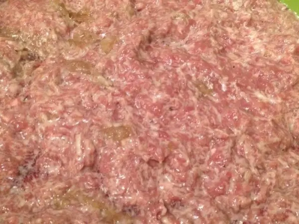 Hackfleisch zeigt eine grobe, fettige Konsistenz und wurde frisch zubereitet, bereit für die Füllung in die Nudelrolle.