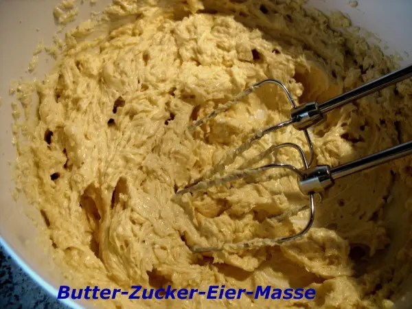 Eine cremige Masse aus Butter, Zucker und Eiern wird mit einem Handmixer in einer Schüssel zubereitet.