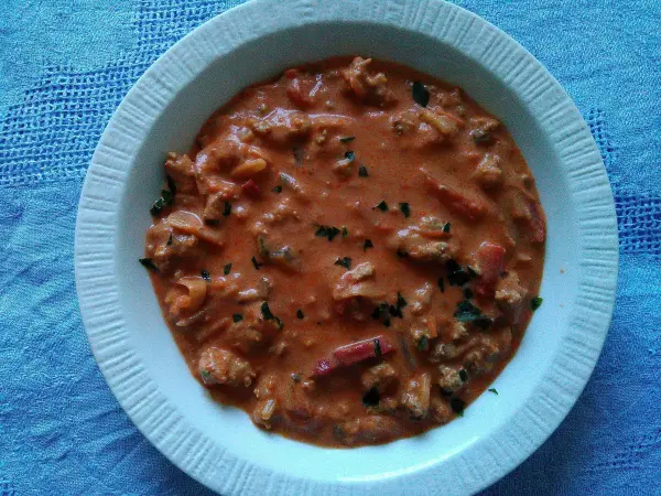 Eintopfgericht in einer Schüssel, es ist eine cremige Hacksuppe, umgeben von einer blauen Tischdecke.