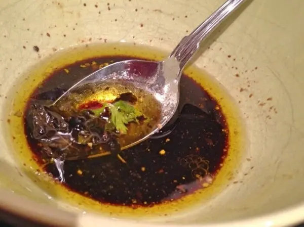 Ein Löffel liegt in einer Schüssel mit dunkler, aromatischer Marinade, die nach Knoblauch und Kräutern duftet.
