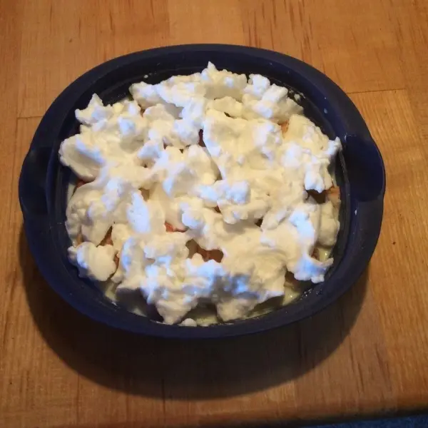 Eine Schüssel Buttermilchkaltschale steht auf einem Holztisch, gefüllt mit einer cremigen, weißen Mischung, ideal für heiße Tage.