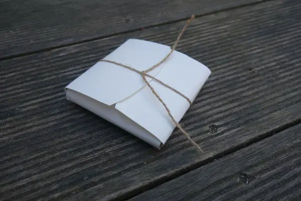 Eine Keksschachtel aus Papier liegt ordentlich auf einer rustikalen Holzoberfläche, mit einer Schnur festgebunden.
