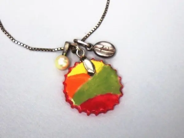 Ein bunter Kettenanhänger aus Fimo hängt an einer Silberkette und zeigt eine kreative Mischung aus Farben und Anhängern.