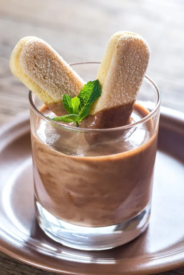 Ein Glas Blitzdessert mit cremigem Nutella und Mascarpone ist mit zwei Biskuits und frischer Minze dekoriert.