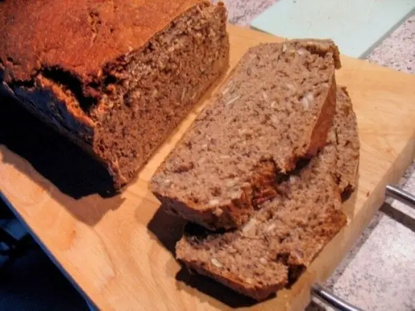 Ein frisch gebackenes, knuspriges Roggen-Mischbrot liegt auf einem Holzbrett, neben mehreren gleichmäßig geschnittenen Scheiben.