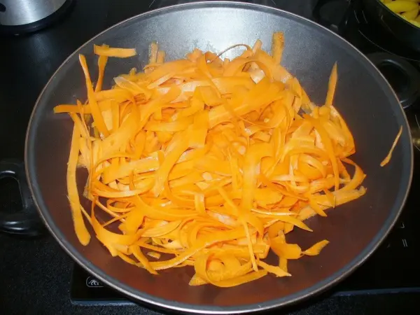 In einer Pfanne wird orangefarbener, geschnittener Möhrensalat leicht angebraten, als Teil einer asiatischen Möhrengemüsepfanne.