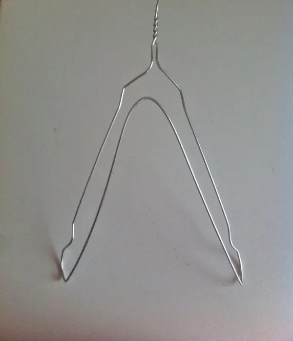 Ein Drahtkleiderbügel hängt an einer Wand und könnte als Zeitunghalter für Zeitungen verwendet werden.